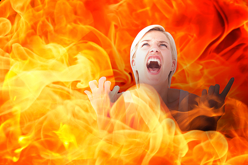 Upset woman screaming with hands up  against fire