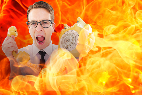 Geeky businessman shouting at retro phone against fire