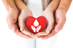 Couple holding miniature heart in hands against blood donation