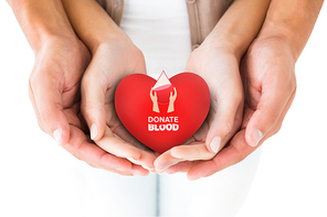 Couple holding miniature heart in hands against blood donation