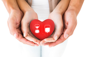 Couple holding miniature heart in hands against blood donation