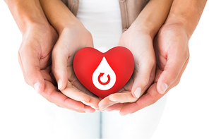 Couple holding miniature heart in hands against donate blood graphic