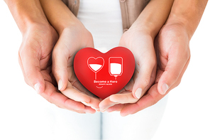 Couple holding miniature heart in hands against blood donation