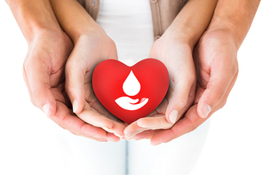 Couple holding miniature heart in hands against blood donation