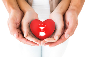 Couple holding miniature heart in hands against blood donation