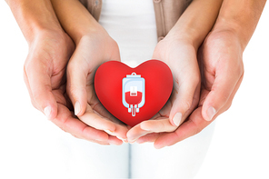 Couple holding miniature heart in hands against blood donation