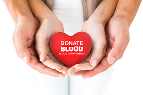 Couple holding miniature heart in hands against blood donation