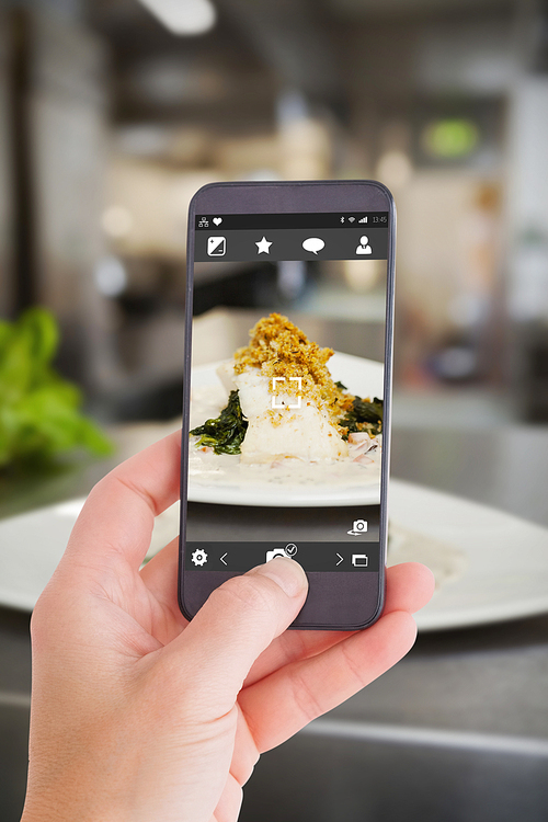 Female hand holding a smartphone against plate of food ready to go