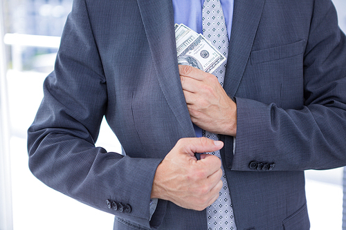 Dodgy businessman pocketing a bundle of dollar bills