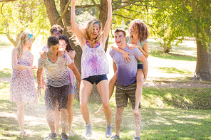 Young friends having fun with hose in the park on a sunny day