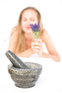 Beautiful blonde lying on massage table with mortar and pestle at the health spa