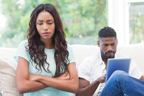 Upset woman being ignored by partner at home in the living room