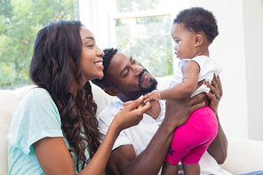 Happy couple with their baby girl on couch at home in the living room