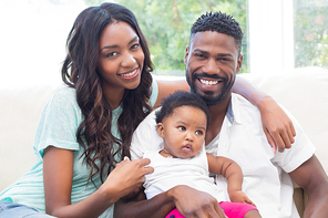 Happy couple with their baby girl on couch at home in the living room