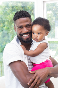 Happy father with baby girl on couch at home in the living room