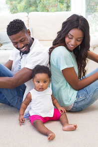 Happy parents with baby girl at home in the living room