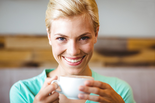 Pretty blonde holding cup of coffee at the cafe