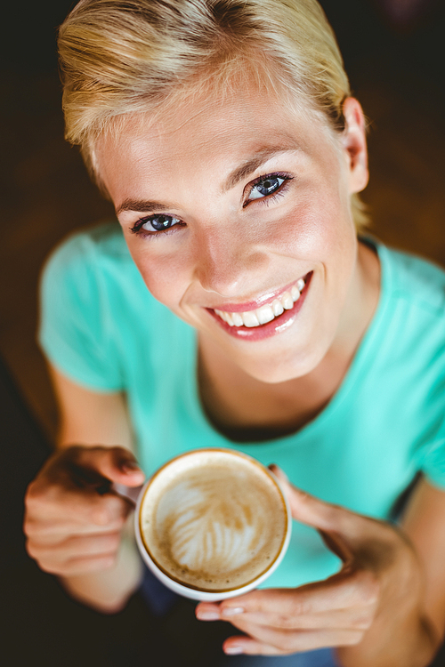 Pretty blonde holding cup of coffee at the cafe