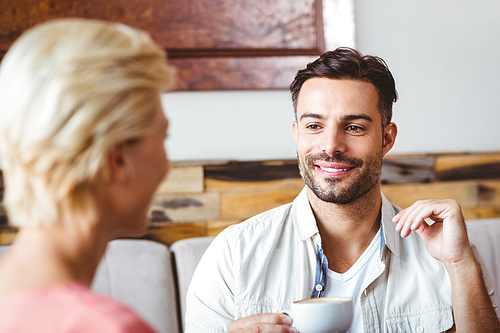 couple with coffee cup sitting on sofa at home