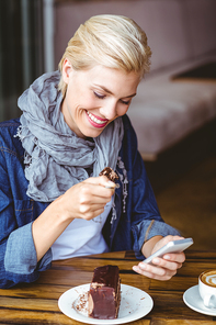 Smiling blonde enjoying a piece of chocolate cake at the cafe