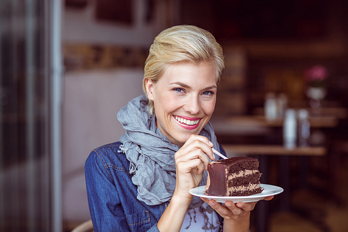Portrait of a smiling blonde taking a piece of chocolate cake
