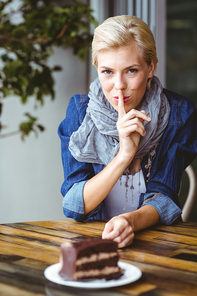 Smiling blonde looking at the camera while gesturing silence