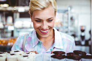 Pretty woman looking at cup cakes at the bakery