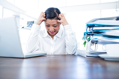 Businesswoman getting stressed at her desk in office