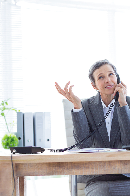 Smiling businesswoman phoning at work in the office