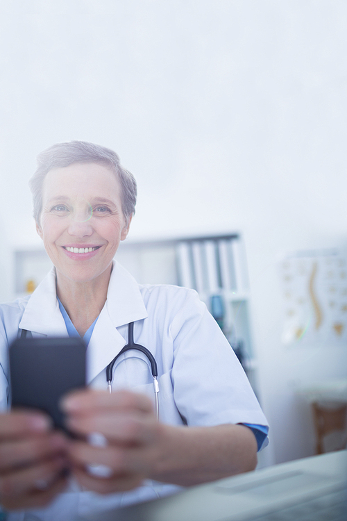 Happy doctor  and using her smartphone in medical office