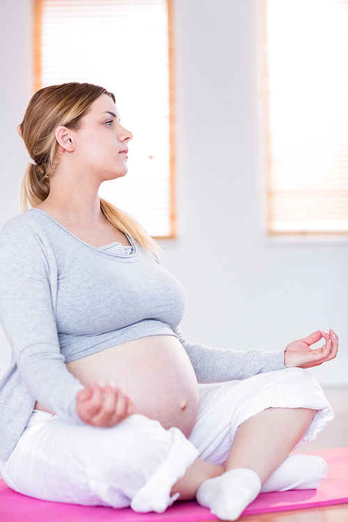 Pregnant woman doing yoga on exercise mat at home