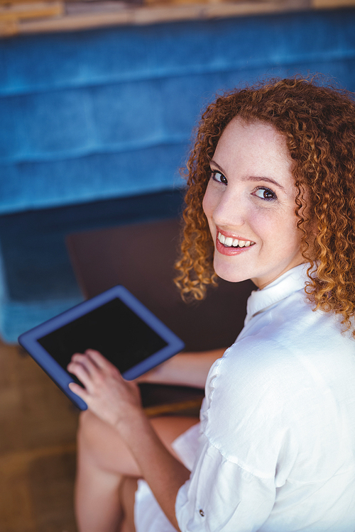 Pretty girl using a small tablet at table in a cafe