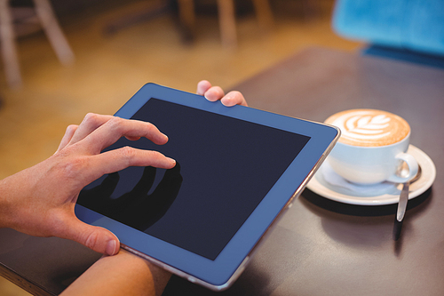 Close-up of digital tablet and coffee on table in the coffee shop