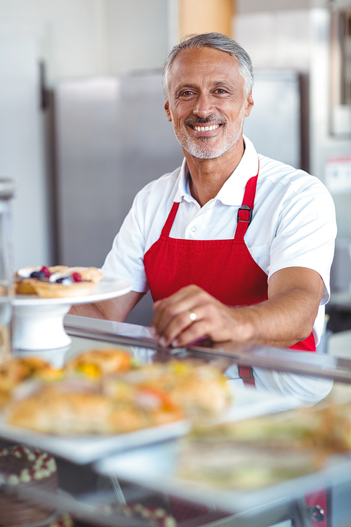 Barista smiling at camera behind counter in the bakery