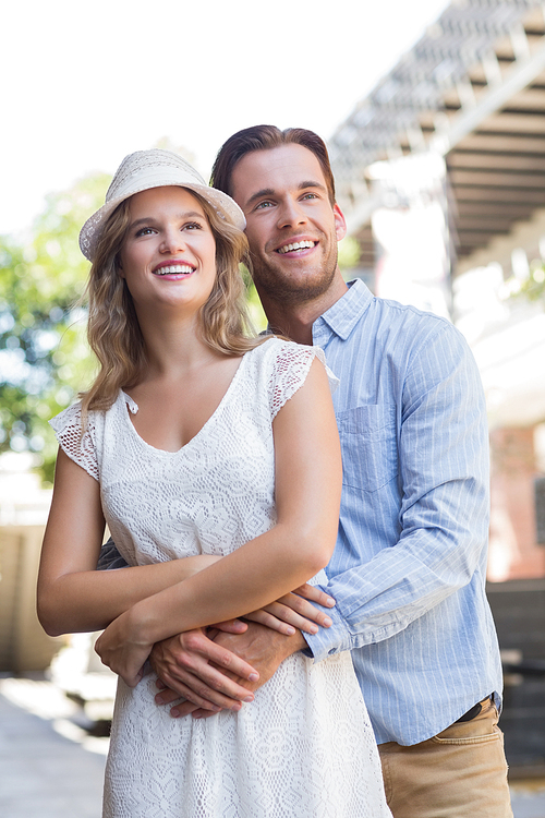 Standing cute couple hugging each other while looking away