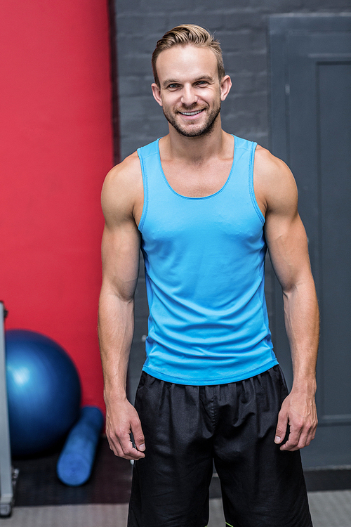 Muscular man smiling at camera at the crossfit gym