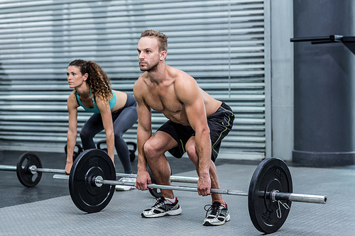 Muscular couple lifting weight together at the crossfit gym