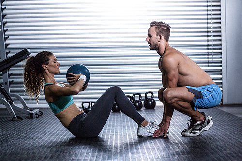Side view of a muscular couple doing abdominal ball exercise