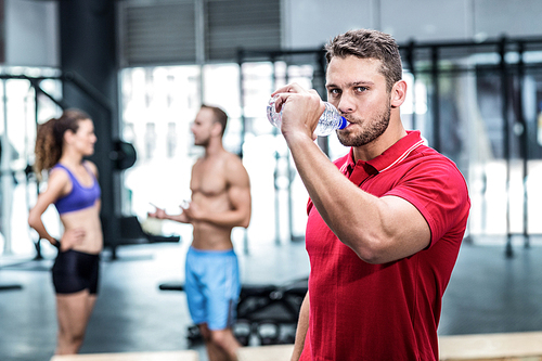 Portrait of muscular trainer with athletes on the background