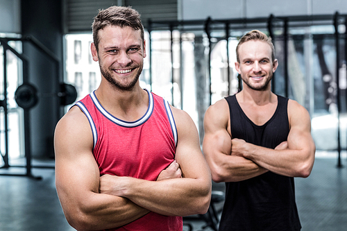 Portrait of two smiling muscular men with arms crossed