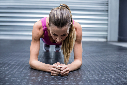 Front view of a muscular woman on a plank position