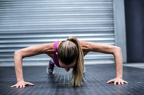Front view of a woman doing push ups at the crossfit gym