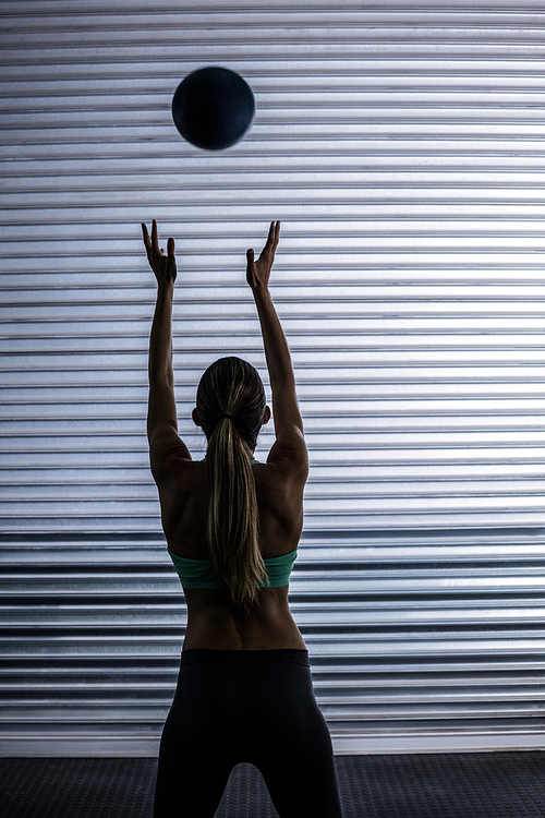 Back view of a muscular woman throwing ball in the air