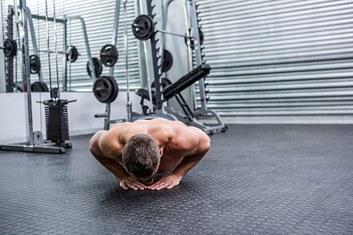 Muscular man doing push-ups in crossfit gym