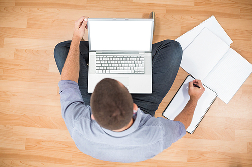 Young creative businessman working on laptop besides a notebook
