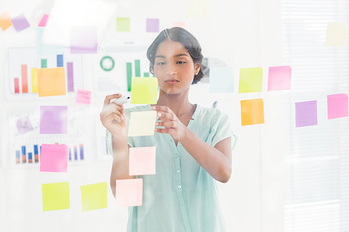 Concentrated businesswoman looking post its on the wall in the office