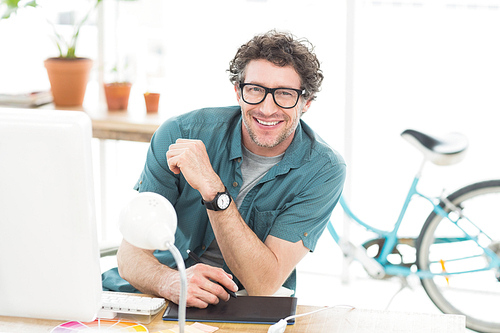 Cheerful graphic designer using a graphics tablet in a modern office