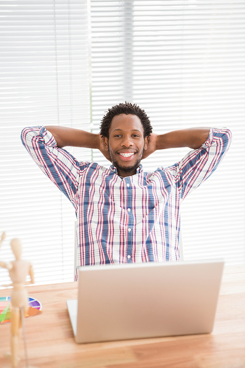 Young businessman relaxing at his desk in front of the laptop in the office