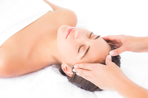 Side view of an attractive young woman receiving head massage at spa center