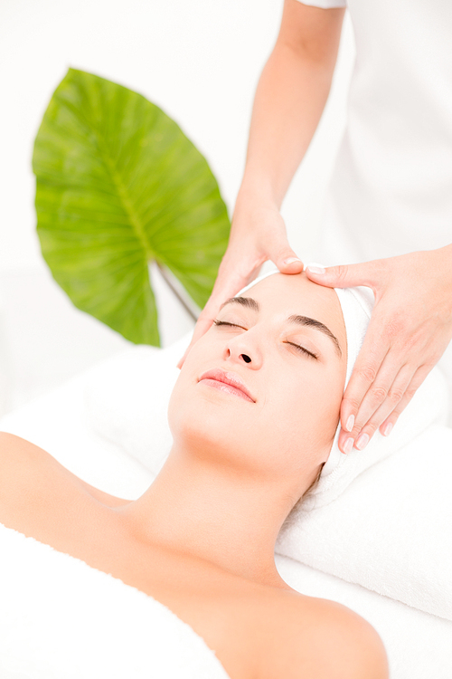 Side view of an attractive young woman receiving facial massage at spa center